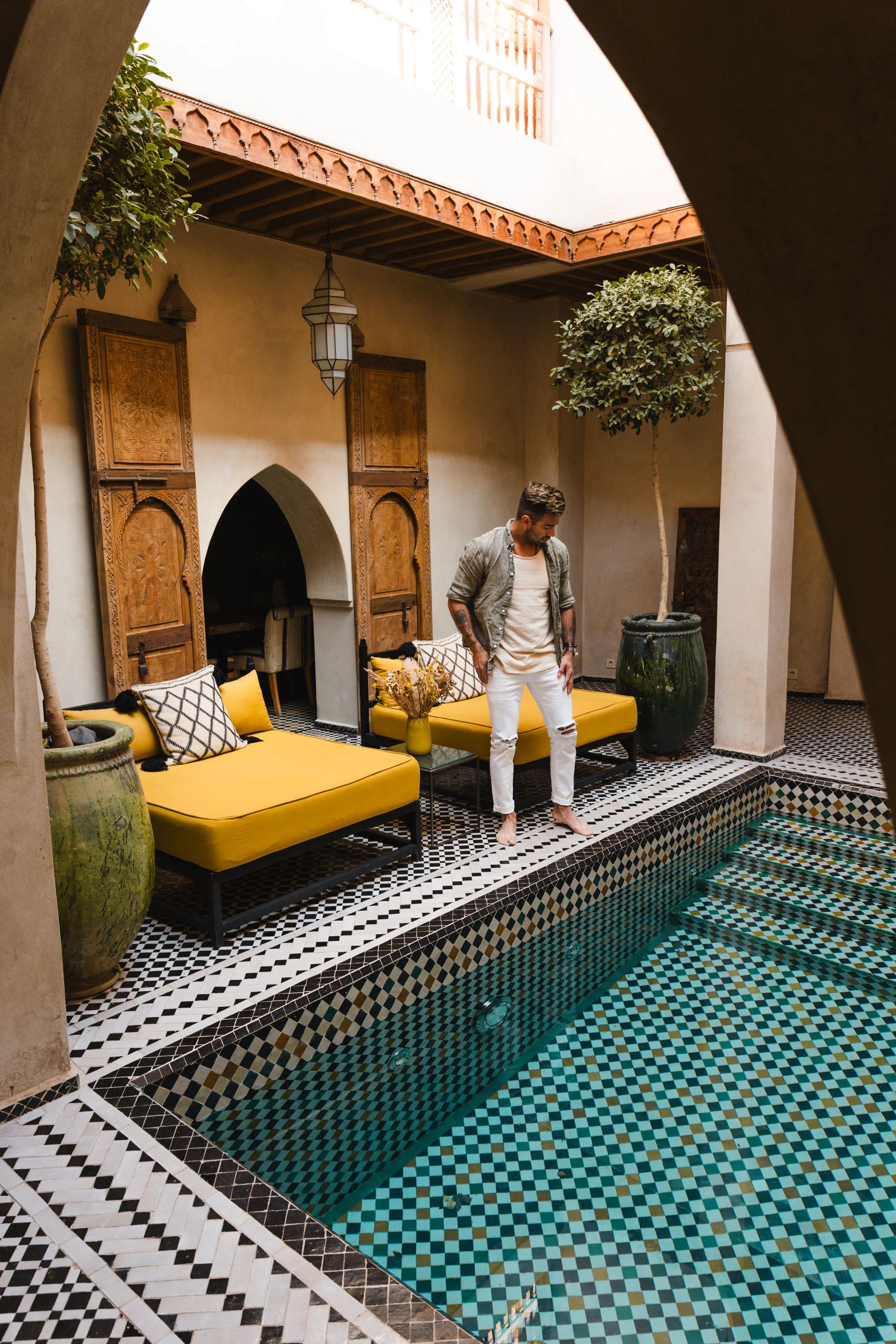 Courtyard plunge pool in patterned tile, daybeds under the arcade