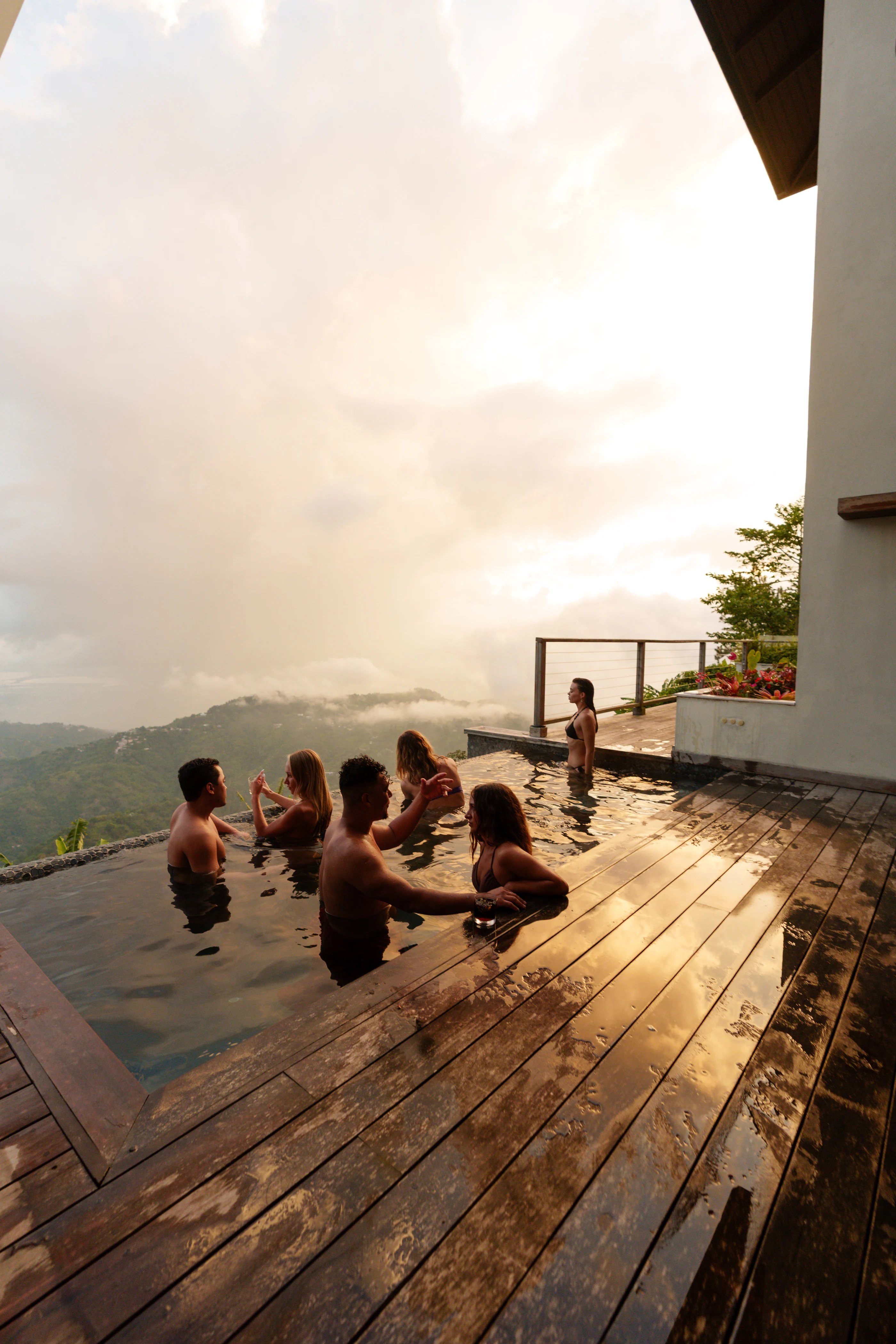 Guests in the infinity pool as the sun goes down behind the ridge