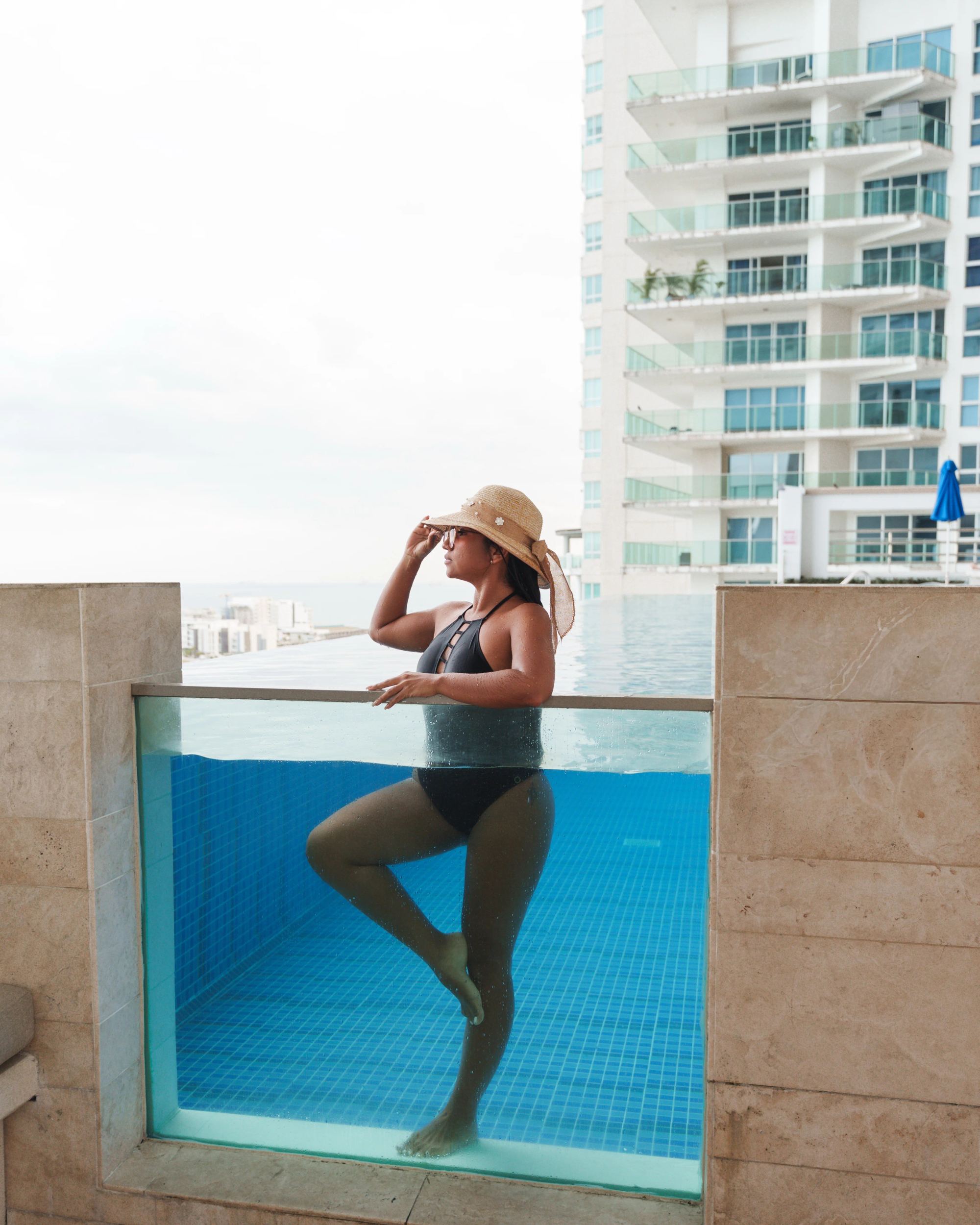 A guest standing in the glass-edged pool on a high terrace